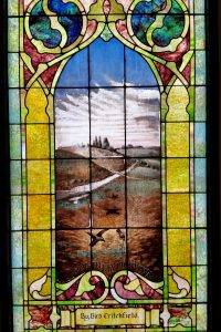 Four windows portray the Parable of the Sower.  Attributed to Jesus, it is found in all of the Synoptic Gospels (at Mark 4:1-20, Matthew 13:1-23, and Luke 8:1-15) as well as in the Gospel of Thomas (Thomas 9). The parable can be interpreted to illustrate different reactions to the gospel message. A sower dropped seed on the path, on rocky ground, and among thorns, and the seed was lost; but when seed fell on good earth, it grew, yielding thirty, sixty, and a hundredfold. The seed is the word or gospel of the kingdom. In this window, the seed has taken root and is flourishing with abundance. The “good ground” represents the one who hears the word and understands it.   
	George Lobingier was born in Pennsylvania December 9, 1832 and after teaching school for a time, studied law. He practiced law for seven years, then decided to prepare himself for the ministry and studied in the biblical department of Hiram College where James A. Garfield (later president of the United States) was his instructor. Lobingier held pastorates in a number of states and in Canada. For some time he preached at the First Christian Church of New York City and also for the church in Washington, D.C. while James A. Garfield was in congress and a regular attendant. While preaching in Thayer County, Nebraska, he was elected and reelected County Judge for three terms beginning in 1883. Lobingier’s wife also grew up in Pennsylvania and while young, listened to the preaching of Charles Louis Loos, a companion of the early fathers of the Christian Church (Disciples of Christ). Charles S. Lobingier, a son, became a noted author and lawyer, serving as a U.S. judge in the Philippines and China.
	This window (which cost $50) was already installed in the church at the time of George Lobingier’s death in April 1909, so the memorial is noted on a piece of clear glass leaded onto the stained glass panel.
